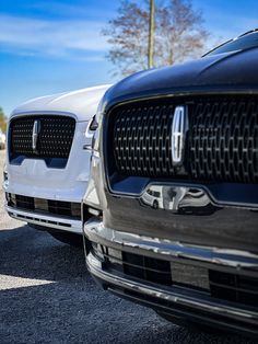 two cars parked side by side in a parking lot with blue sky and clouds behind them