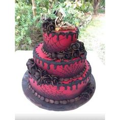 a three tiered cake with red and black icing on the bottom, topped with a skeleton figurine