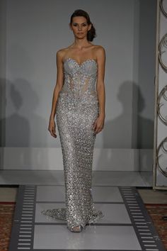 a model walks down the runway in a silver gown