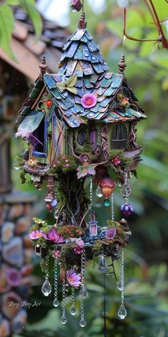 a bird house with lots of colorful decorations hanging from it's roof