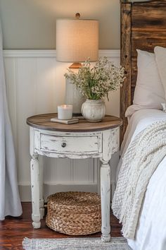 a bedroom with a bed, nightstand and lamp on the side table in front of it