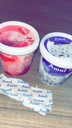 two yogurt cups are sitting next to each other on a table with one cup filled with ice cream