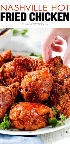 a white plate topped with fried chicken covered in sauce and garnished with parsley