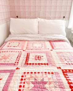 a pink and white quilt on a bed