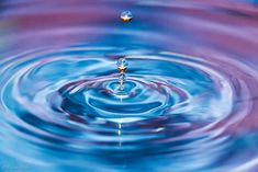 a blue and purple water droplet is seen in this image