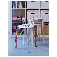 two white stools with red and white ribbons on them in front of a bookcase