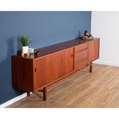 a wooden sideboard sitting on top of a hard wood floor next to a blue wall