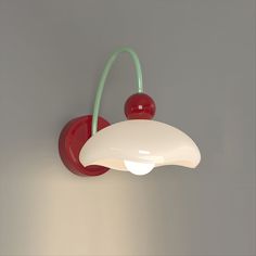 a red and white wall mounted light with two cherries on the top of it