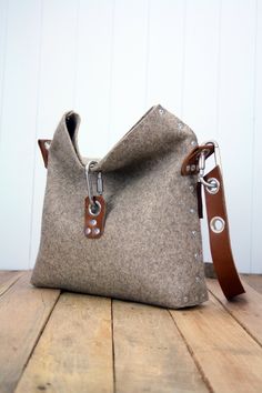 "Felt Handbag which is handmade in England, from 3 mm industrial wool felt, and is assembled using pop rivets. The strap is made and attached to the bag using 100% vegetable tanned full-grain leather which is backed with felt to add another tactile feeling. The bag folds over and fastens with carabiner, and there are two internal pockets for your phone and wallet, as well as pen holders and a space to keep your travel card. Dimensions: Length       10\" / 25cm Width       13\" / 33cm Depth 4\" / Felt Cross, Felt Handbag, Felt Clutch, Women's Purses, Felted Handbags, Womens Handbag, Top Handbags, Handmade Handbags, Felt Bag