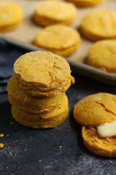 some cookies are stacked on top of each other next to a baking pan with more cookies in the background