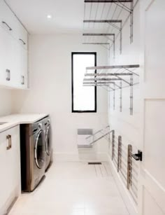 a washer and dryer in a white laundry room with stainless steel shelving