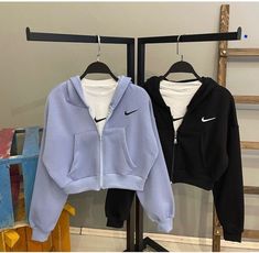 two sweatshirts hanging on clothes racks in front of a wall with shelves and ladders