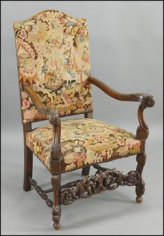 an ornately decorated arm chair with carved wood frame and fabric upholstered seat