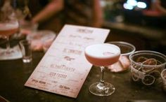 there is a menu and some glasses on the bar table with people in the background