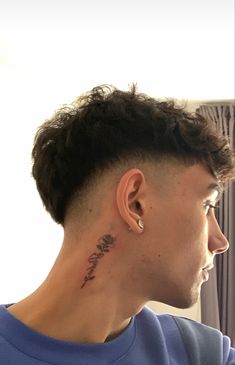 a man with a tattoo on his neck and behind his ear looking out the window