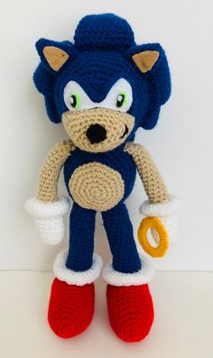 a crocheted sonic the hedge doll is posed on a white surface with red and blue shoes