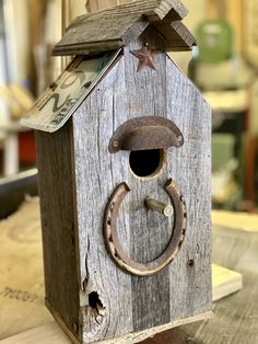 a wooden birdhouse with a metal ring on it's door and a star hanging from the roof