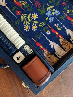 a wooden table with a blue rug and several different types of items in it, including a leather case