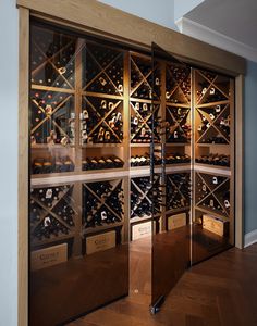 a wine cellar with glass doors and shelves filled with lots of bottles on the wall