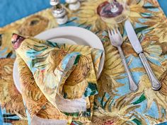 a place setting with sunflower napkins and silverware