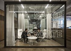 a person sitting at a desk in front of a glass wall with the words space create on it