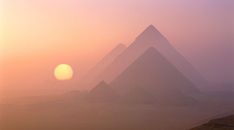 three pyramids in the desert with foggy sky