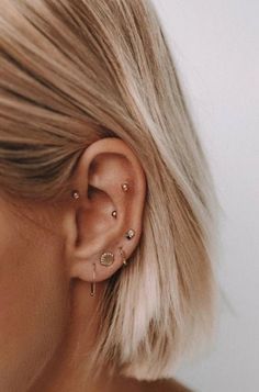 a woman with blonde hair is wearing an ear cuff and has two piercings on her ears