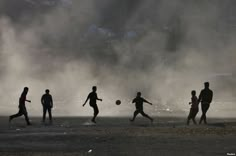 silhouettes of people playing soccer on the beach