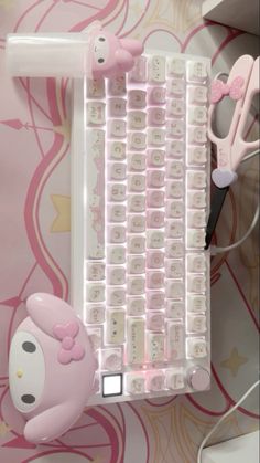 a keyboard with hello kitty key board attached to the back side and some scissors next to it