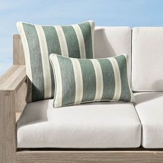 two pillows sitting on top of a white couch next to a wooden table and chair