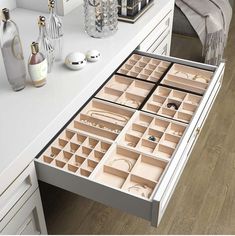 an open drawer on a white dresser filled with jewelry