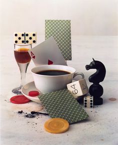 a cup of coffee sitting on top of a table next to dice and other items