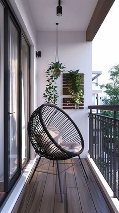 a black chair sitting on top of a wooden floor next to a plant in a pot