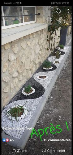 an outdoor garden with rocks and plants on the side of a building in front of a window