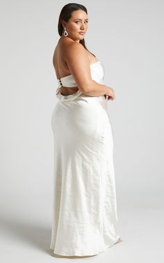 a woman in a white dress posing for the camera with her hands on her hips