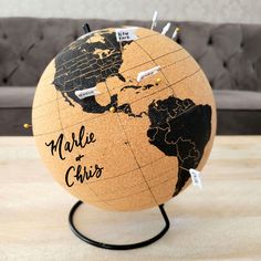 a wooden globe with pins stuck to it on a table in front of a couch