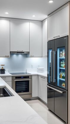 a modern kitchen with stainless steel appliances and white counter tops, along with marble flooring