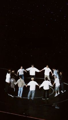 a group of people holding hands on top of a black surface with stars in the background