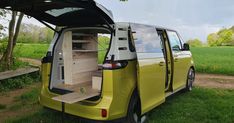 a yellow van is parked in the grass with its doors open and it's hatch opened