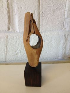 a wooden sculpture with a circular hole in it's center on a wood block