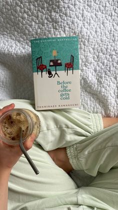 a person is holding a jar of coffee while laying on the bed with their legs crossed