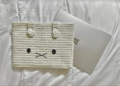 a white crocheted bag sitting on top of a bed next to a laptop computer