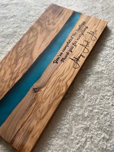 a piece of wood with writing on it sitting on the floor next to a white carpet