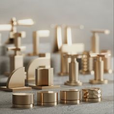 several different sizes and shapes of brass objects on the floor in front of a gray wall