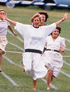 three women running on a race track with their arms in the air and one woman holding her hands out