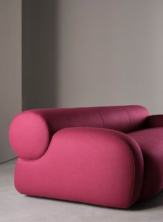 a pink couch sitting on top of a white floor next to a gray wall in an empty room