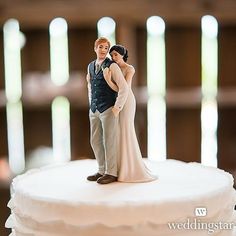 a bride and groom figurine standing on top of a white frosted cake