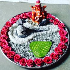 there is a decorative plate with red flowers and an elephant statue on the table top