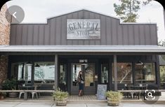 a woman standing in the doorway of a building with tables and chairs outside it that reads general store