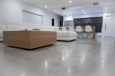 a living room filled with white furniture next to a wooden table and chairs on top of a hard wood floor